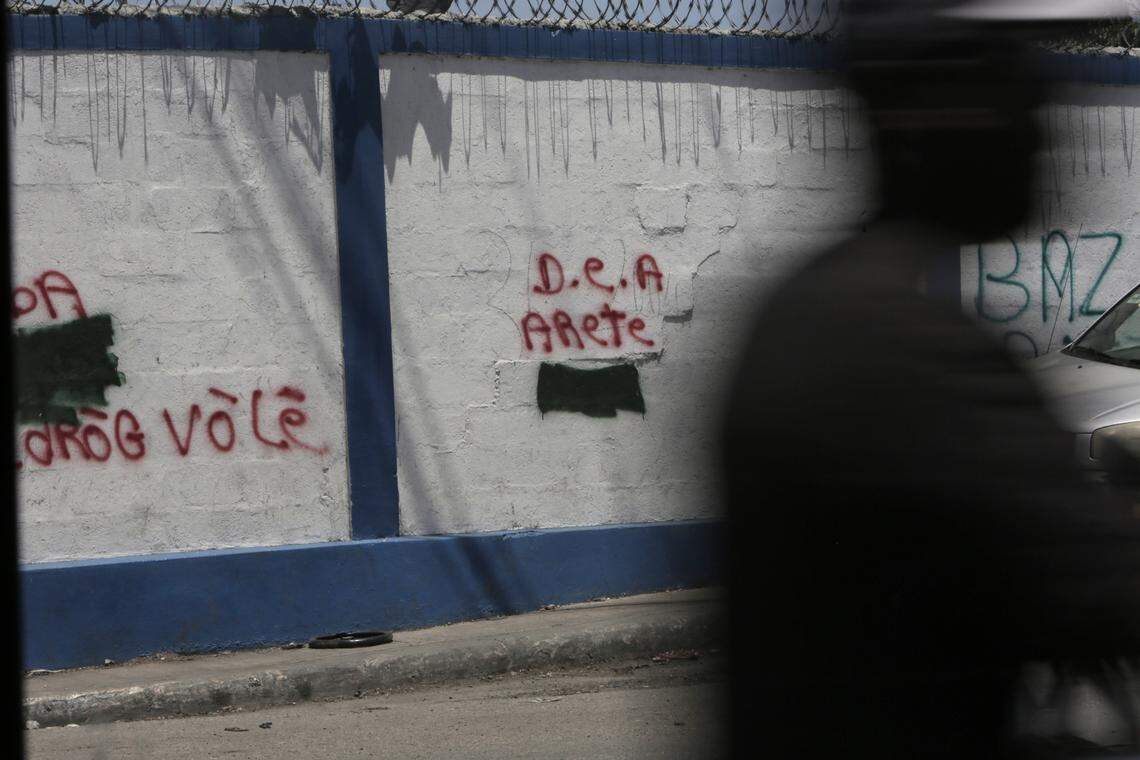 A man walks past the walls to the government port in Port-au-Prince, Haiti, where graffiti on the wall pleads for the DEA to make an arrest.