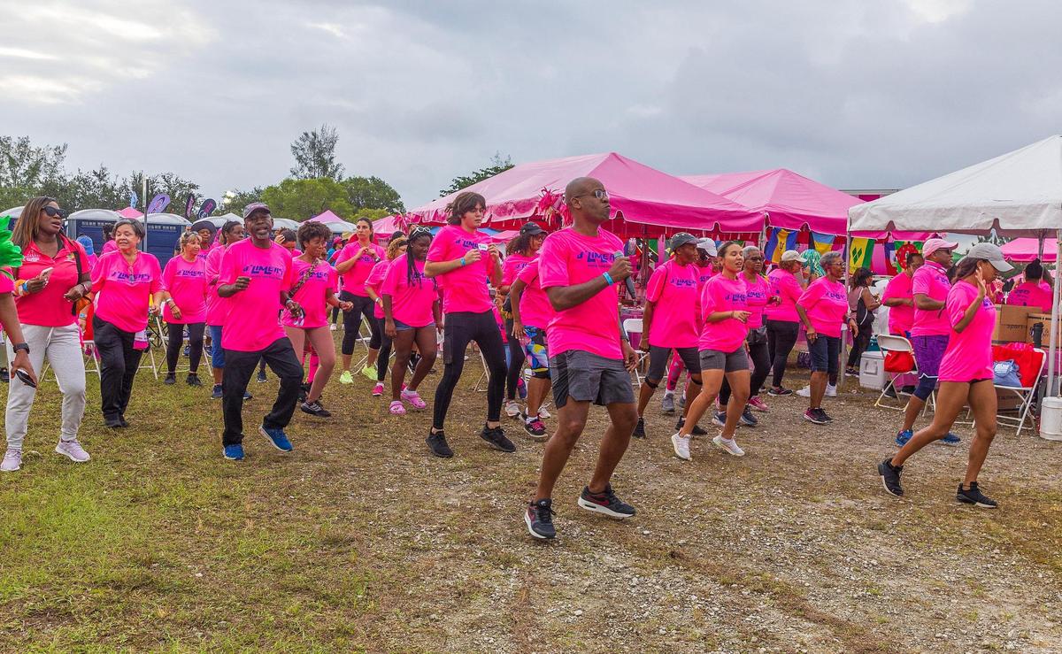 Marlon Hill (front) leads a warm up of members of the d’limers team who were among thousands who joined the 2023 Susan G. Komen MORE THAN PINK Walk at Amelia Earhart Park in Hialeah on Saturday, Oct. 14, 2023.