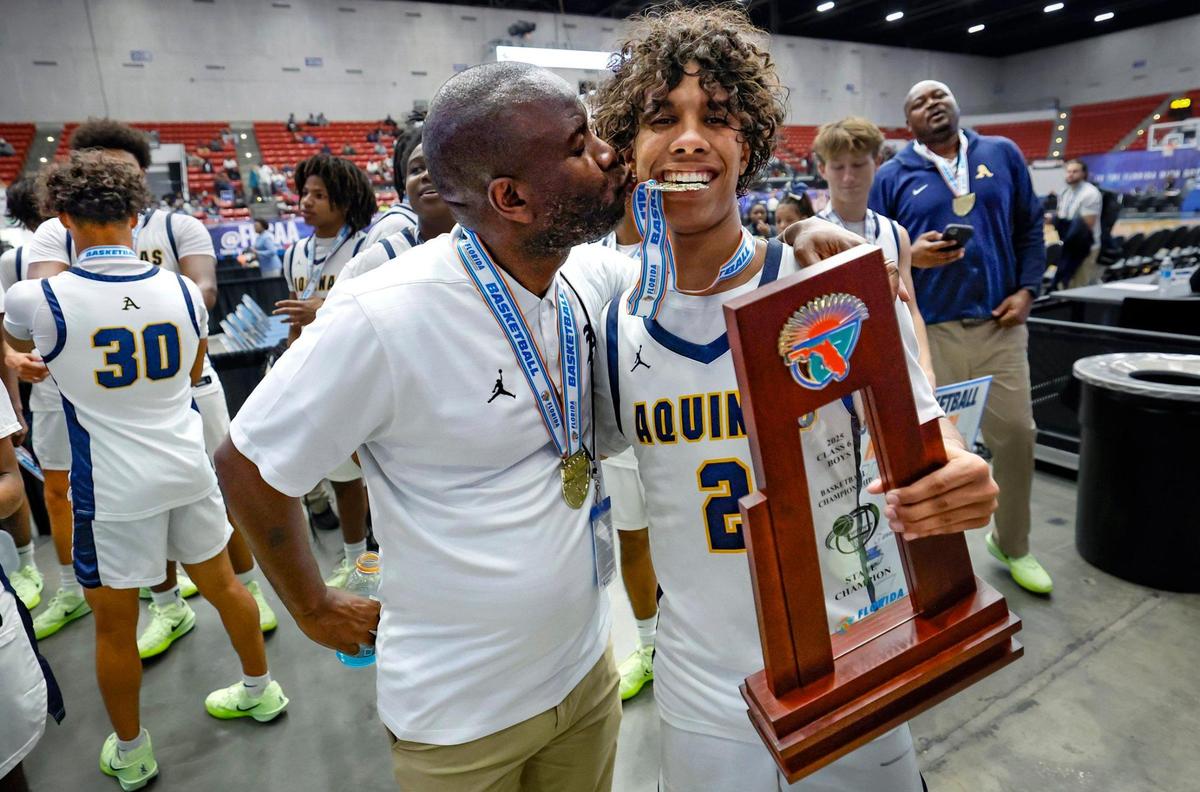 St. Thomas Aquinas Raiders head coach Julius Sandi kisses his son DJ Sandi (2) as they celebrate the win over Evans for the FHSAA Class 6A Boys High School Basketball State Championship at the RP Funding Center in Lakeland, Florida on Saturday, March 8, 2025.
