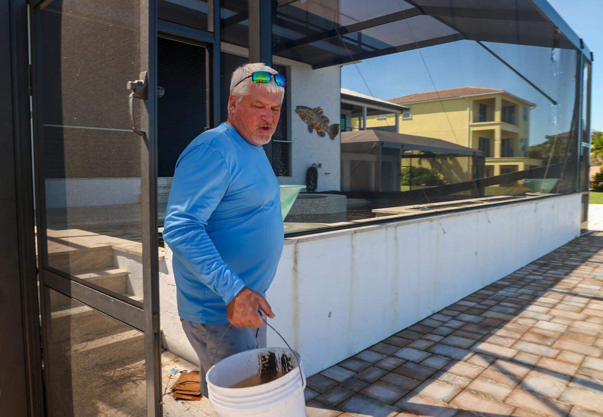 Home builder Steve Ondrejka, 58, carries buckets of storm water from his pool as he and family members clean out their home damaged by Hurricane Milton on Thursday, October 10, 2024, in Matlacha, Florida.