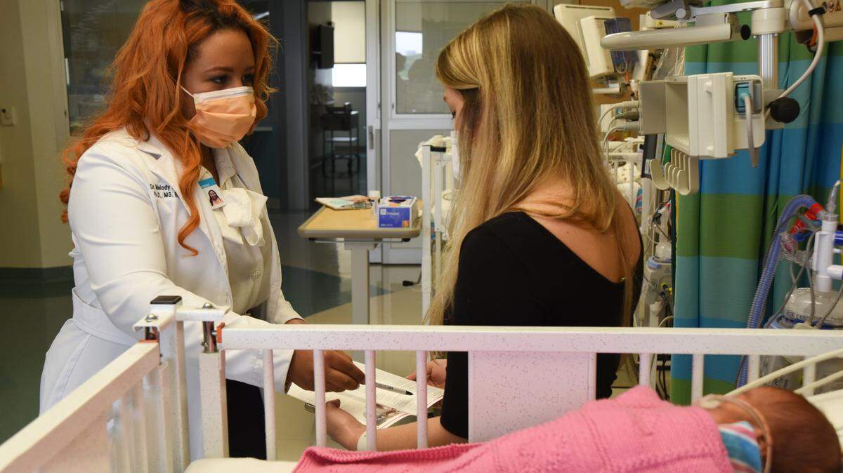 From left, Melody Hernandez, the lead RN in the Baby Steps program at Nicklaus Children’s Hospital, explains how the program provides telehealth home visits led by nurses to parents of premature infants after they leave the NICU at Nicklaus. Sarah Priestley-Akhtar, right, had twin premature infants in the neonatal intensive care unit at Nicklaus for nearly four months.