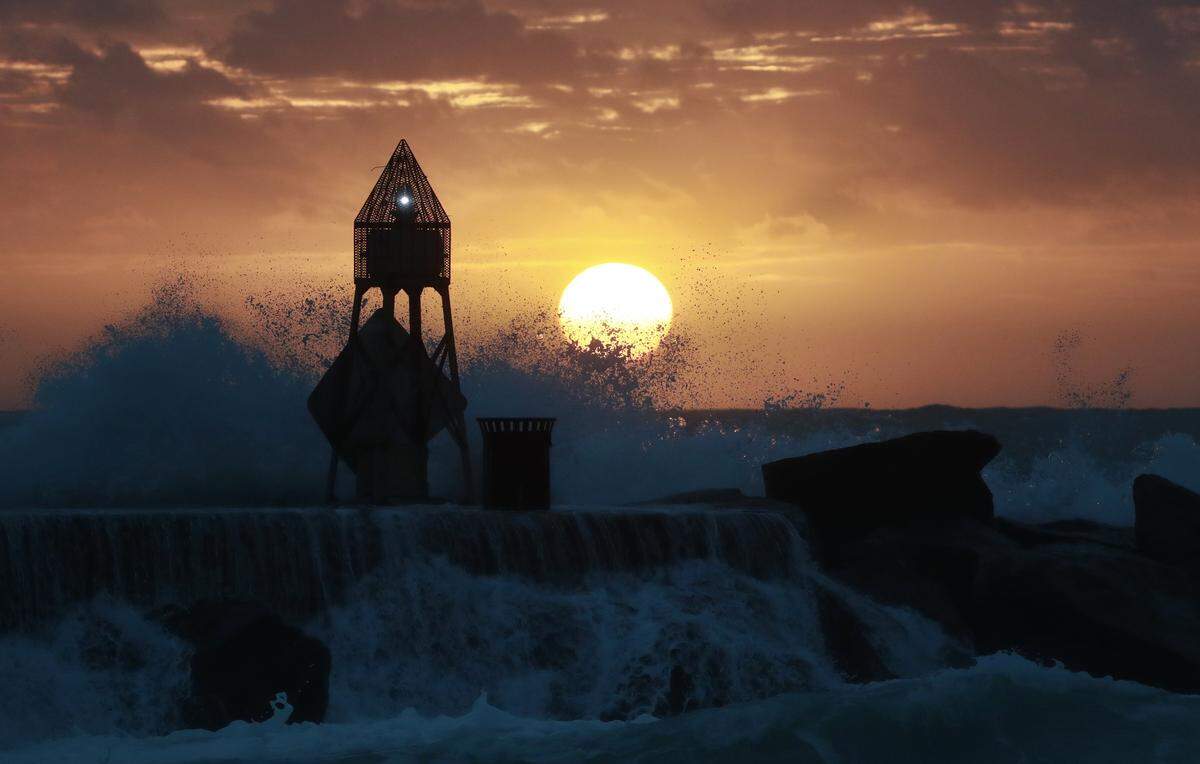 Large waves crash over a jetty as the sun rises over the Atlantic Ocean, Wednesday, Jan. 23, 2019, in Bal Harbour, Fla. According to the National Weather Service, hazardous marine conditions and a high risk of rip currents are possible for the beaches along with isolated strong to severe thunderstorms possible late tonight.