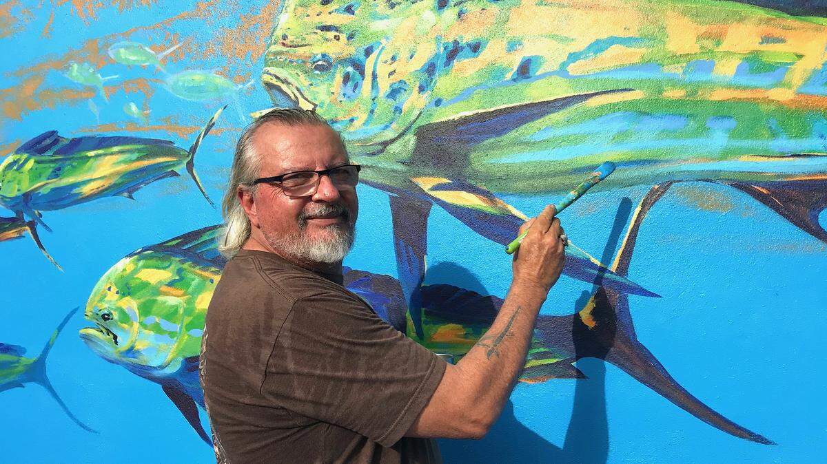 Marine wildlife artist Pasta Pantaleo of Islamorada works on a mural featuring a school of dolphin that he painted on the back wall at Shenanigan’s Pub & Barbecue in Dania Beach.