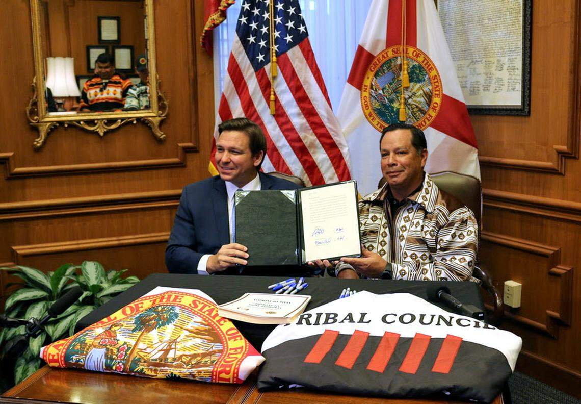 Gov. Ron DeSantis and Marcellus Osceola Jr., chairman of the Seminole Tribe, hold up the gaming compact that they signed in April 2021.