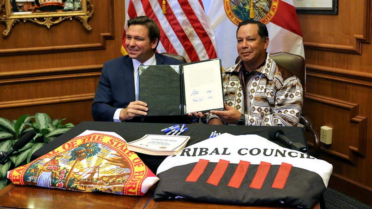 Gov. Ron DeSantis and Marcellus Osceola Jr., chairman of the Seminole Tribe, hold up the gaming compact that they signed in April 2021.