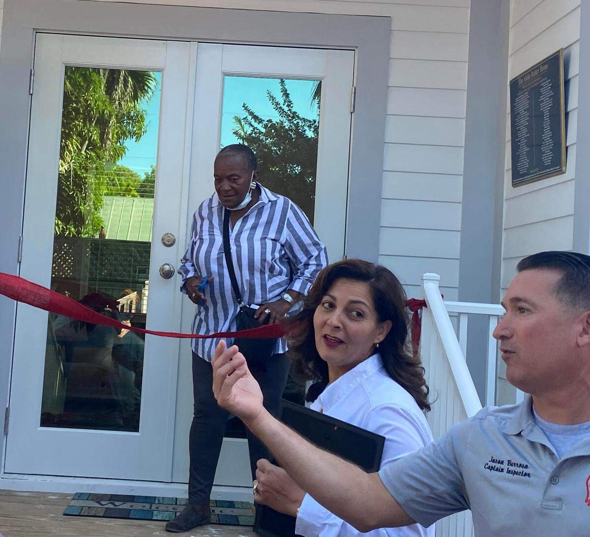 Alelia Butler, center, prepares to cut the red ribbon on the new home on Dec. 22, 2021.