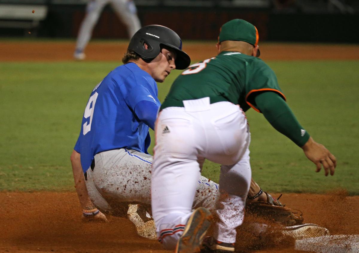 Duke Blue Devils pinch runner Damon Lux (9) slides into third base as Miami Hurricanes third baseman Willy Escala (9) applies the tag following an exceptional throw by Jordan Lala Thursday, May 16, 2019 at Mark Light Field.