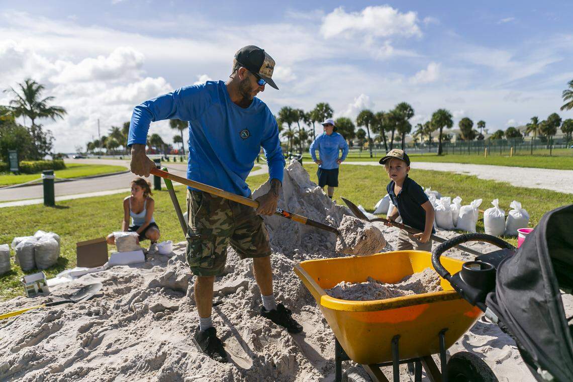 Dewitt Smith, 37, center, and his son, Knox Smith, 5, fill a wheelbarrow with sand in preparation for Hurricane Dorian at Jaycee Park near their home on Hutchinson Island on Friday, August 30, 2019.