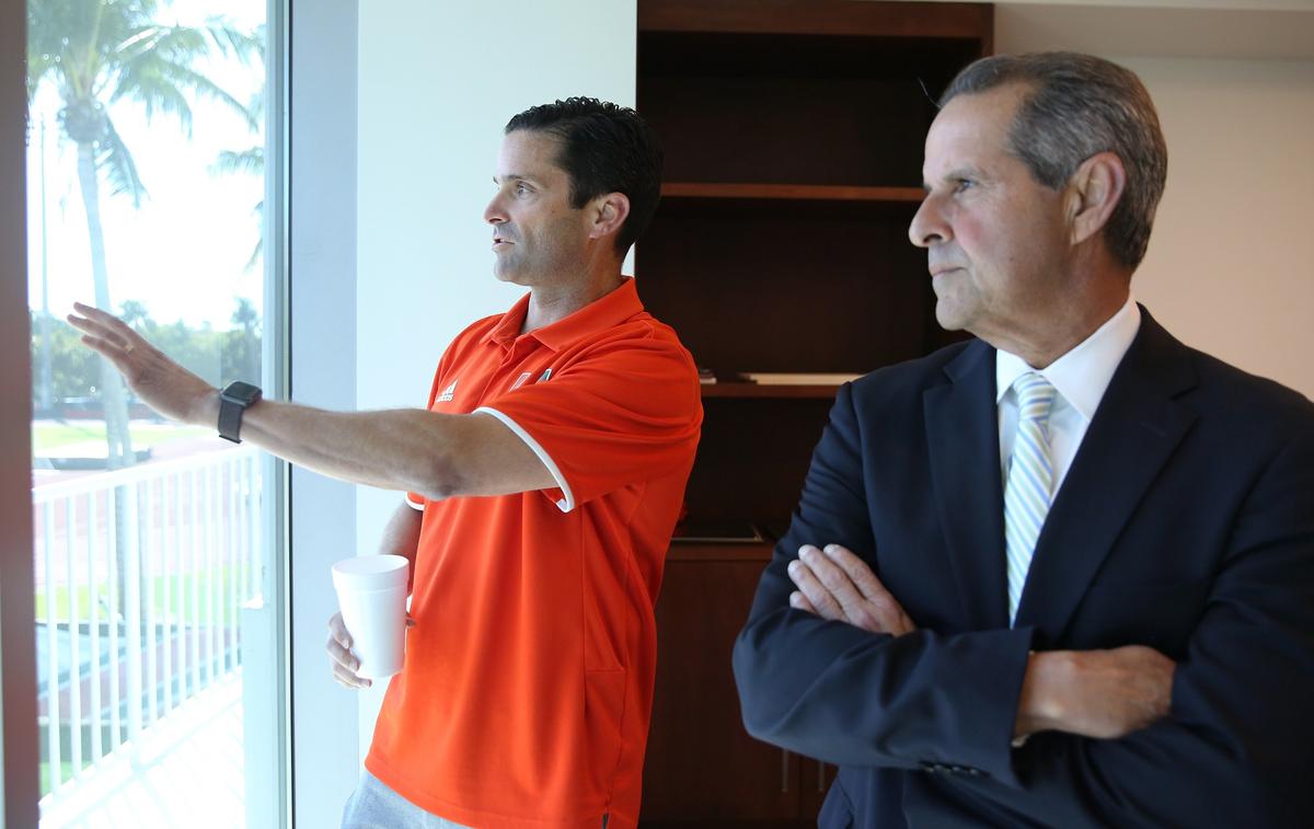 Manny Diaz, Jr., the head football coach at the University of Miami, talks with his father Manny Diaz, Sr., the former Mayor of Miami Wednesday, March 6, 2019, about the new practice fields being installed outside of his office window at UM.