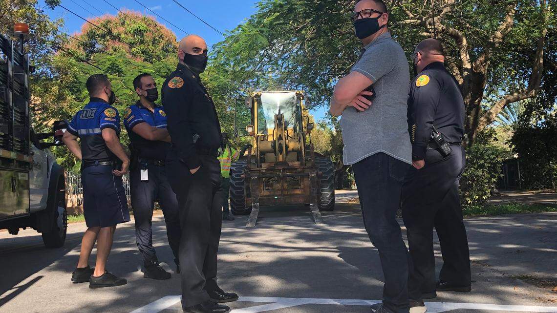 Miami city police gather in front of an idle county fork lift after preventing a Miami-Dade public works crew from removing street-closing barriers in the Silver Bluff neighborhood on Friday, March 5, 2021.