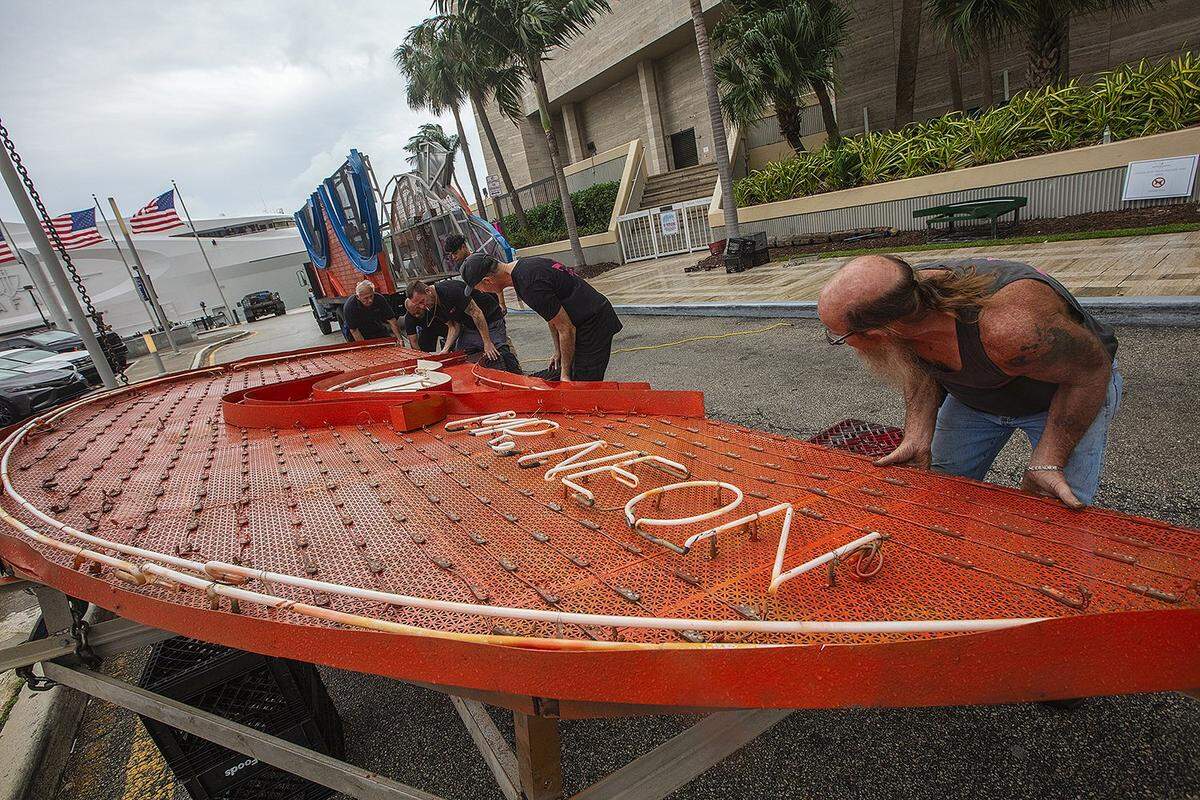From left to right, Steve Carpenter, known as “Mr. Neon,” Hubert Santos, Joe Holley, and Bill Flaherty work together on the Big Orange installation, a beloved Miami NYE tradition, on Friday, December 27, 2024, at the InterContinental Hotel in Downtown Miami.