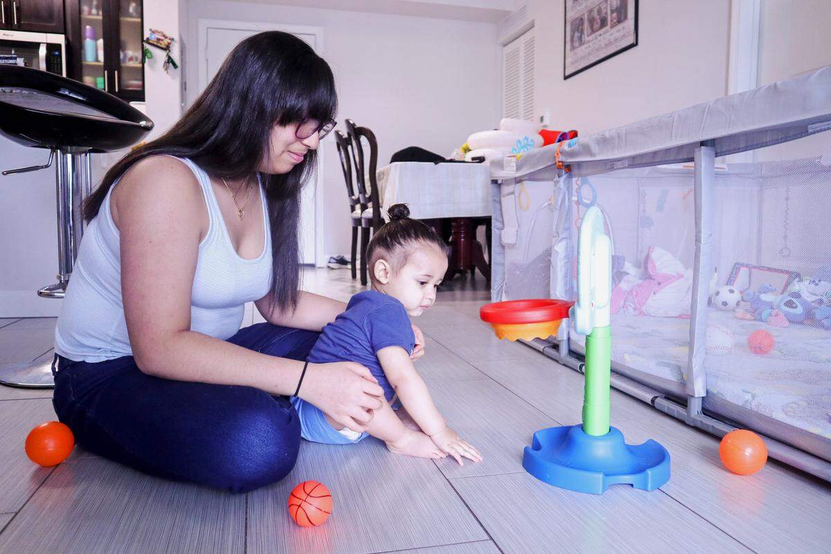 Wilangelys plays with a toy basketball hoop and plastic balls with JJ  