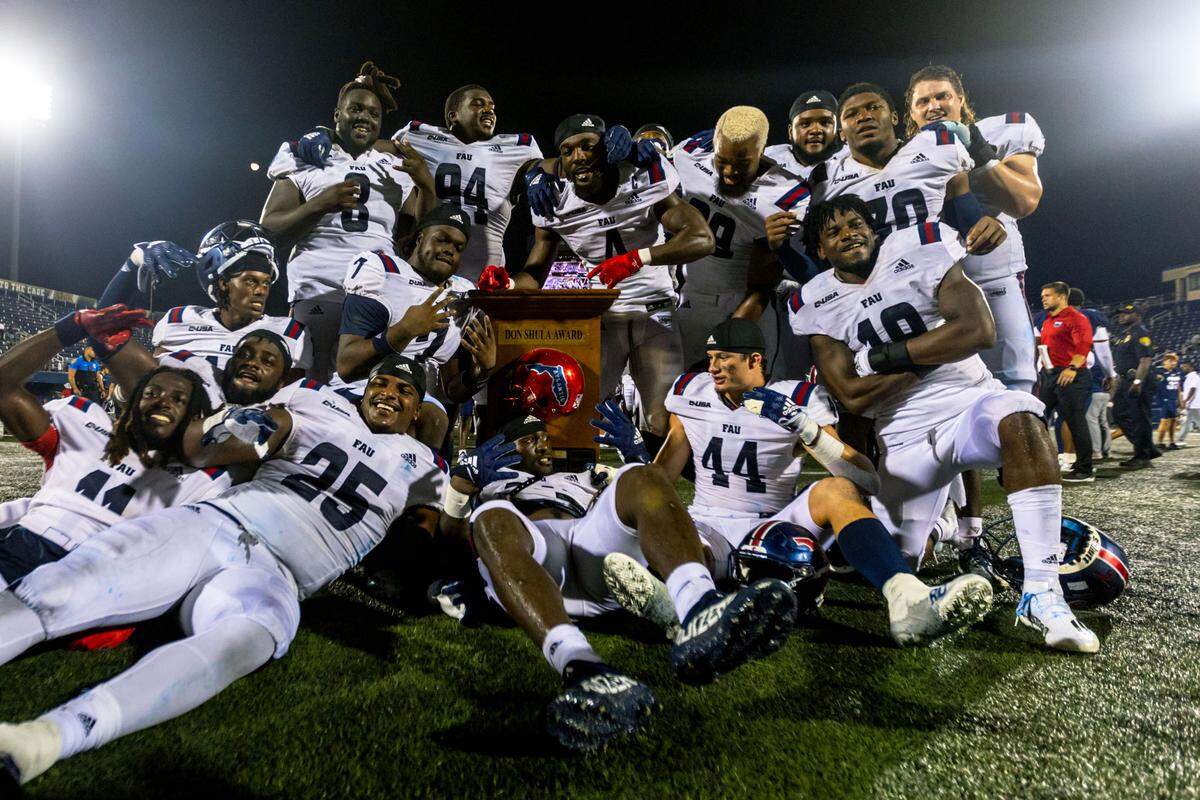 FAU players strike a pose with the Shula Bowl trophy after beating FIU 52-7 at Riccardo Silva Stadium in Miami, Florida, on Saturday, November 12, 2022.
