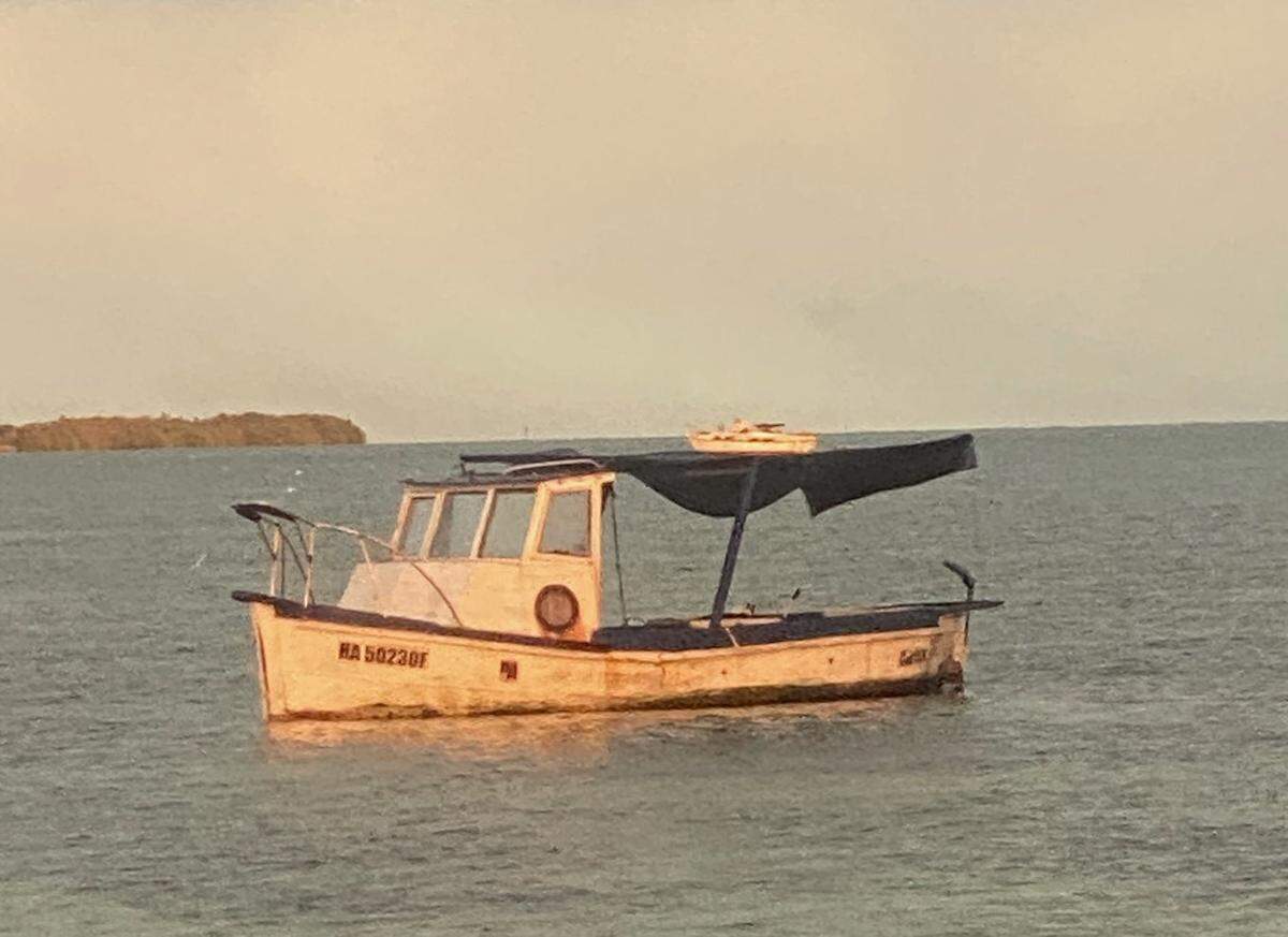 A wooden fishing boat floats in shallow water off Key West Sunday, Feb. 27, 2022. The Border Patrol said 13 people arrived on the vessel.
