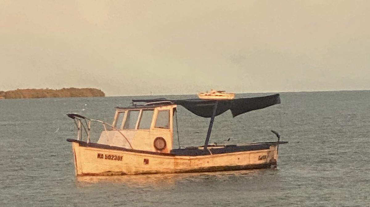A wooden fishing boat floats in shallow water off Key West Sunday, Feb. 27, 2022. The Border Patrol said 13 people arrived on the vessel.