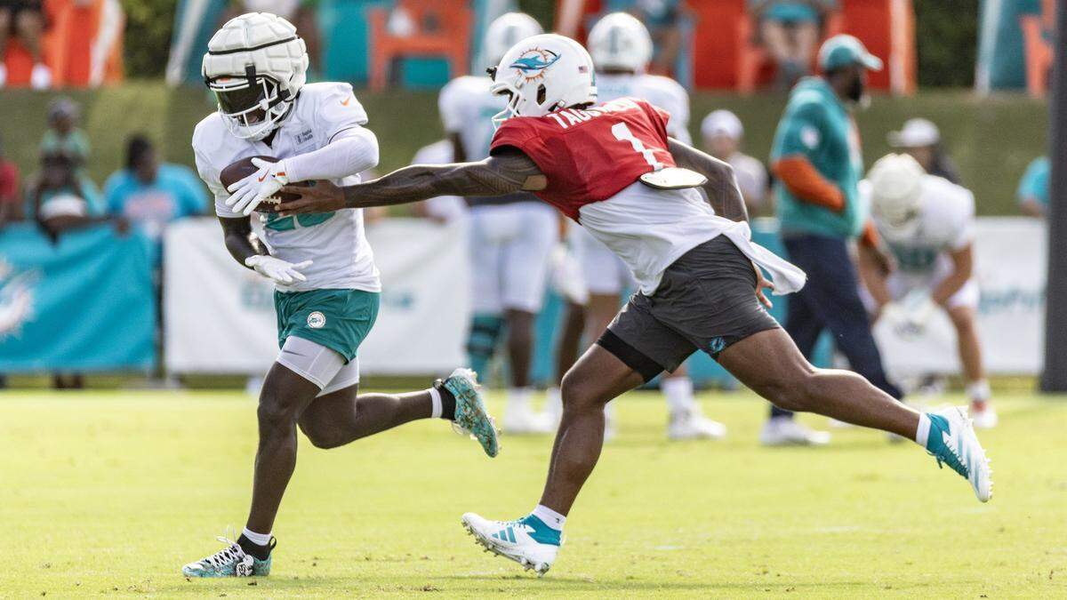 Miami Dolphins quarterback Tua Tagovailoa (1) hands off to running back De'Von Achane (28) during practice at the Miami Dolphins Training Camp