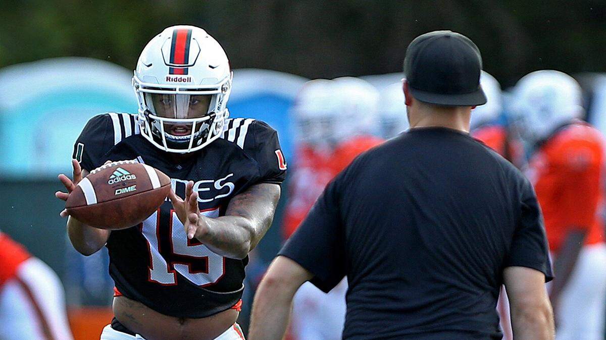 University of Miami quarterback #15 Jarren Williams takes a snap as quarterbacks coach Jon Richt looks on during practice at the Greentree practice field on Monday, August 13, 2018. Williams was not seen during the portion of practice open to the media on Tuesday, August 14, 2018.