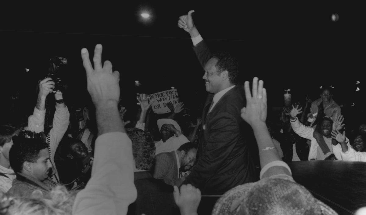 In this file photo, Jesse Jackson gestures to a crowd of Haitians as he leaves Little Haiti on 54th street where he had just delivered a speech on current affairs in Haiti.