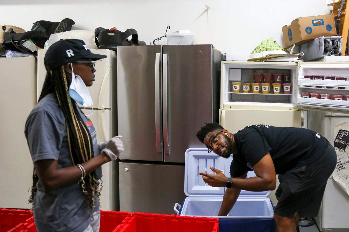 George Caesar talks with Sherina Jones while storing his smoothies in a fridge at Village Free(dge) on Saturday, Oct. 16, 2021.