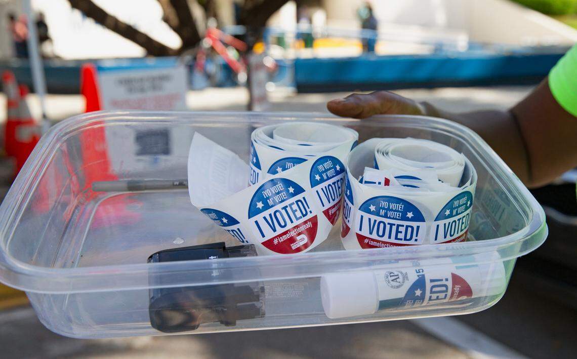 A polling worker holds a tray with vote stickers at the official drop box outside the Miami Beach City Hall during early voting for the general election on Wednesday, October 28, 2020, in Miami Beach.