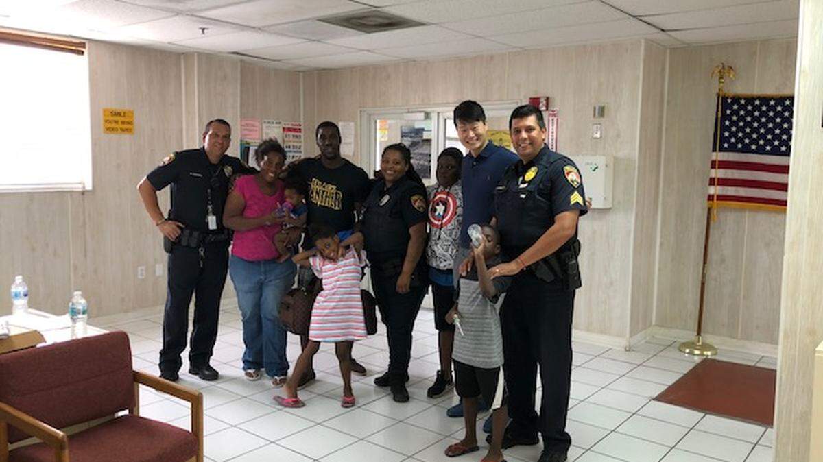The Eason-Dansby family poses for a photo with Terence Huang, the general manager at the Opa-locka Hialeah Flea Market, and officers Jamesha McKinney, Ruben Borrero and Michael Steel. Dewayne Eason says the generosity of Opa-locka's officers and retailers 'hit me in a spot I've never been touched before.'