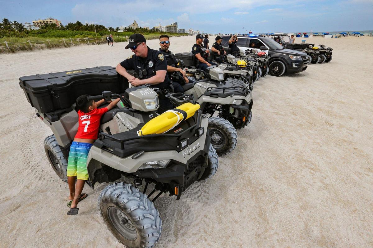 Talen Bharati, de cinco años, de Toronto, habla con el agente Cruz de la policía de Miami Beach, en South Beach, el jueves 17 de marzo de 2022.
