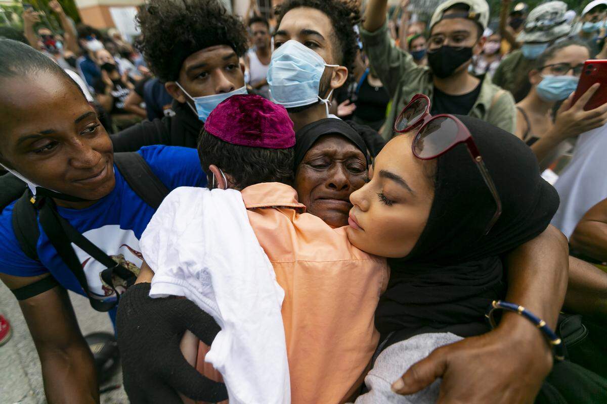 Elaine Williams, 62, center, receives hugs from activists after she spoke during a ‘Justice for George Floyd’ protest near the Miami-Dade State Attorney’s Office in Miami’s Allapattah neighborhood.