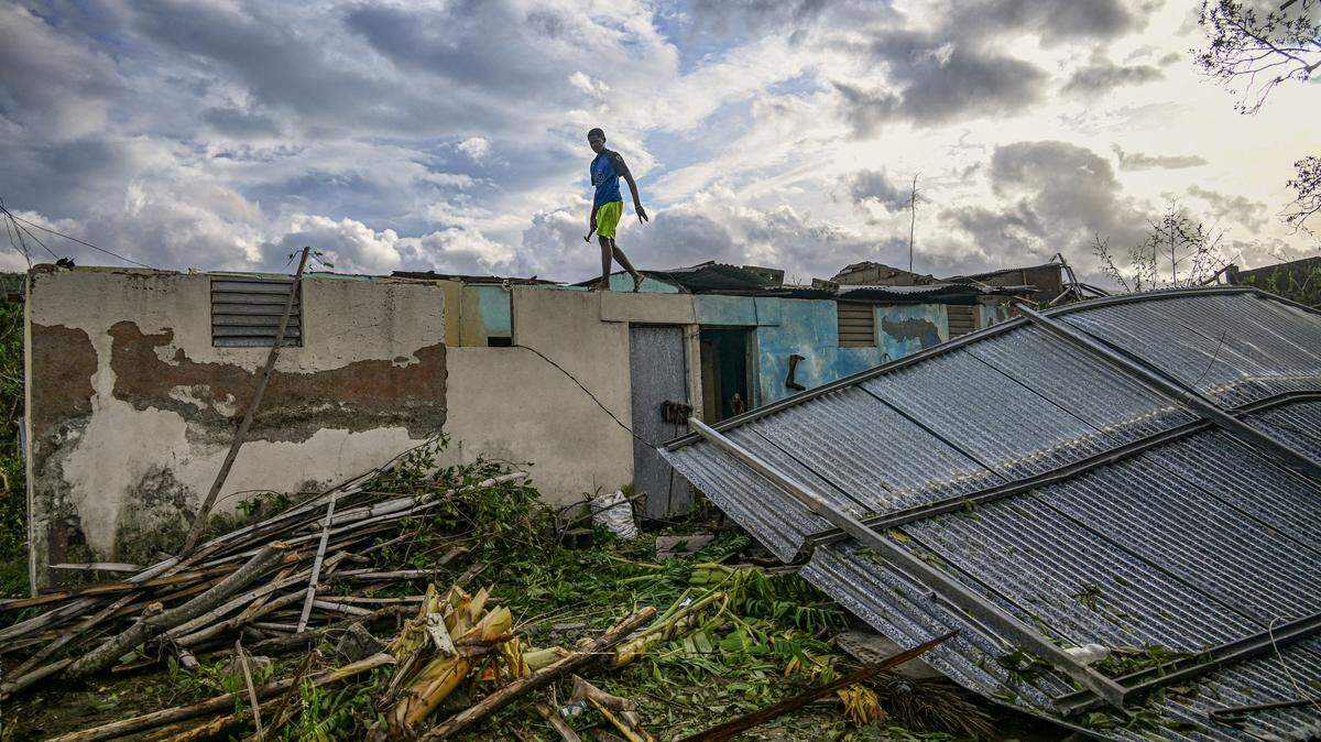 A resident of the town of El Cobre, in the province of Santiago de Cuba, walks on the roof of his damaged home after the passage of Hurricane Melissa, on October 29, 2025. 