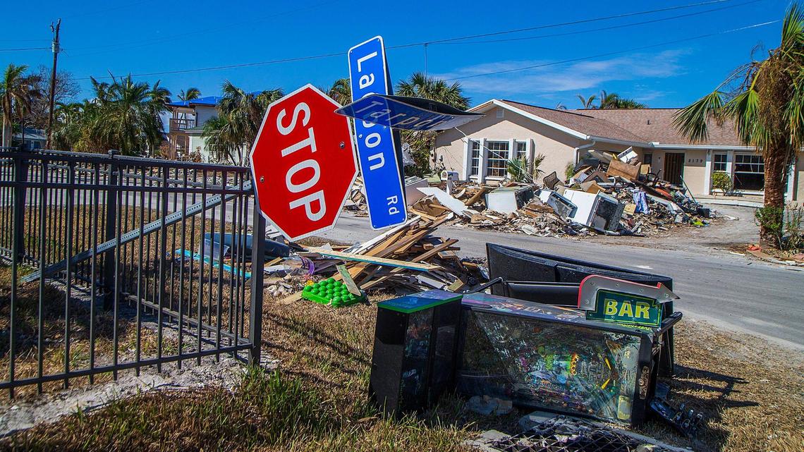 A downed stop sign rests on a fence on the corner of Lagoon and Tarpon roads in Fort Myers Beach, next to items like a pinball machine and appliances, Wednesday, Oct. 26, 2022. The items were among tons of debris left behind in the aftermath of Hurricane Ian, which hit the area as a Category 4 storm a month earlier.