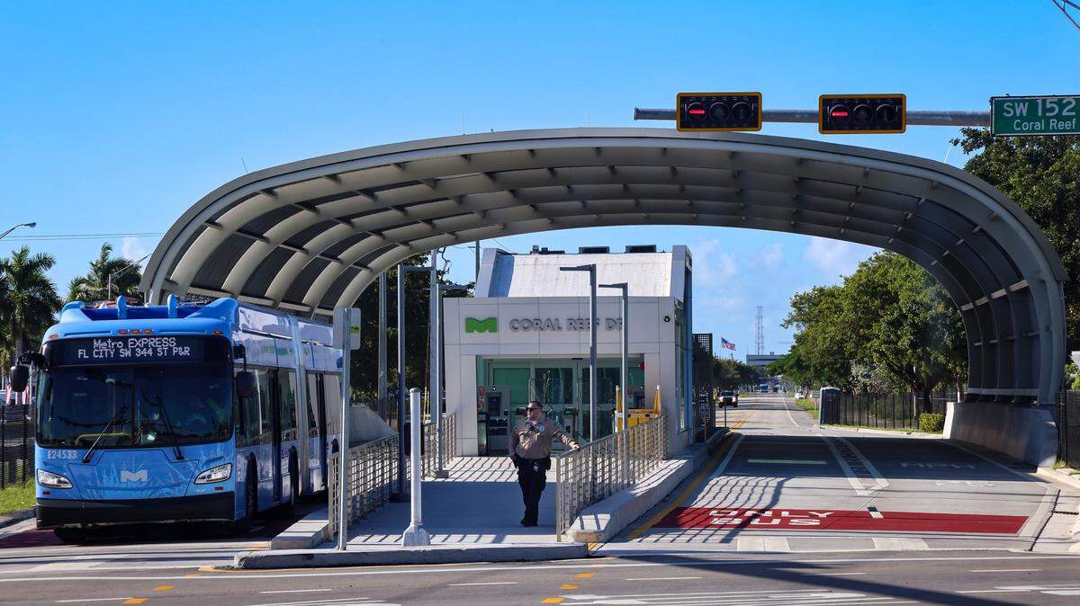 Express line bus stops for the frequent red light while as transit guard J. Sandfiel assures that bus commuters safely enters the station on the first day of Miami-Dade's $300 million rapid-transit bus line known as “Metro Express” on Monday, October 27, 2025, just west of Richmond Heights on Coral Reef Drive and U.S. 1. Many first day riders complained about crowded buses and long travel times due to red lights on the express lane.