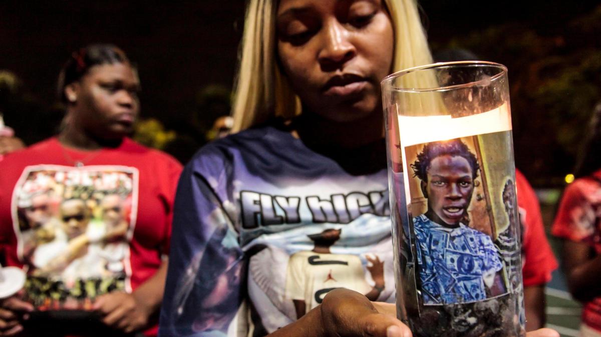 Rahkeen Brown, shown in the photograph on the candle, died in October 2015. His sister, Rontisha Brown, honors her brother at a candlelight vigil in Liberty City on Tuesday, Jan. 1, 2019.