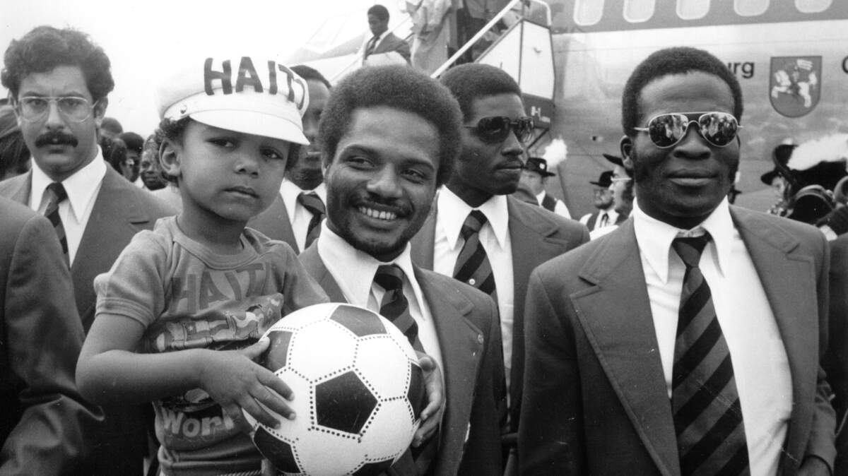 Miro Magloire, 3 1/2 years old at the time, is photographed with Haitian soccer players Fritz Leandre and Emmanuel Sanon as Haiti’s 1974 World Cup team arrived in West Germany on June 4, 1974. He became the team’s unofficial mascot.