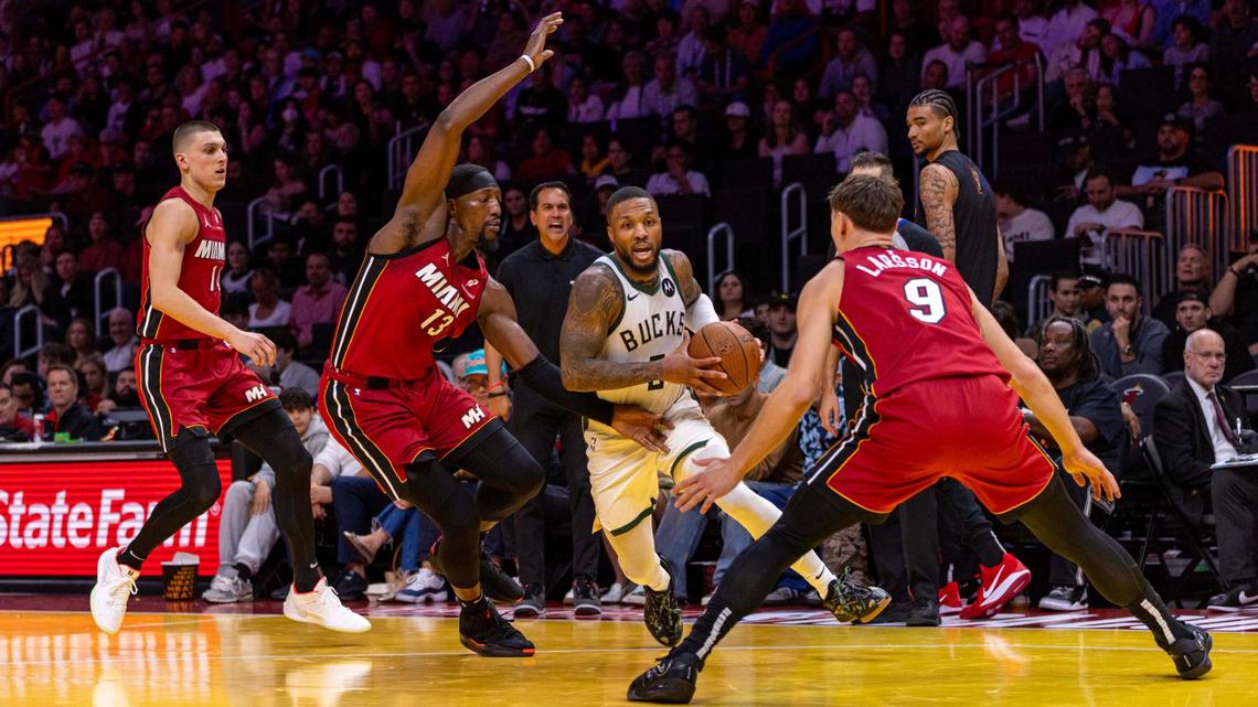 Milwaukee Bucks guard Damian Lillard (0) dribbles toward the rim while defended by Miami Heat center Bam Adebayo (13) and guard Pelle Larsson (9) during the second half of an NBA game at Kaseya Center on Nov. 26, 2024, in Miami.