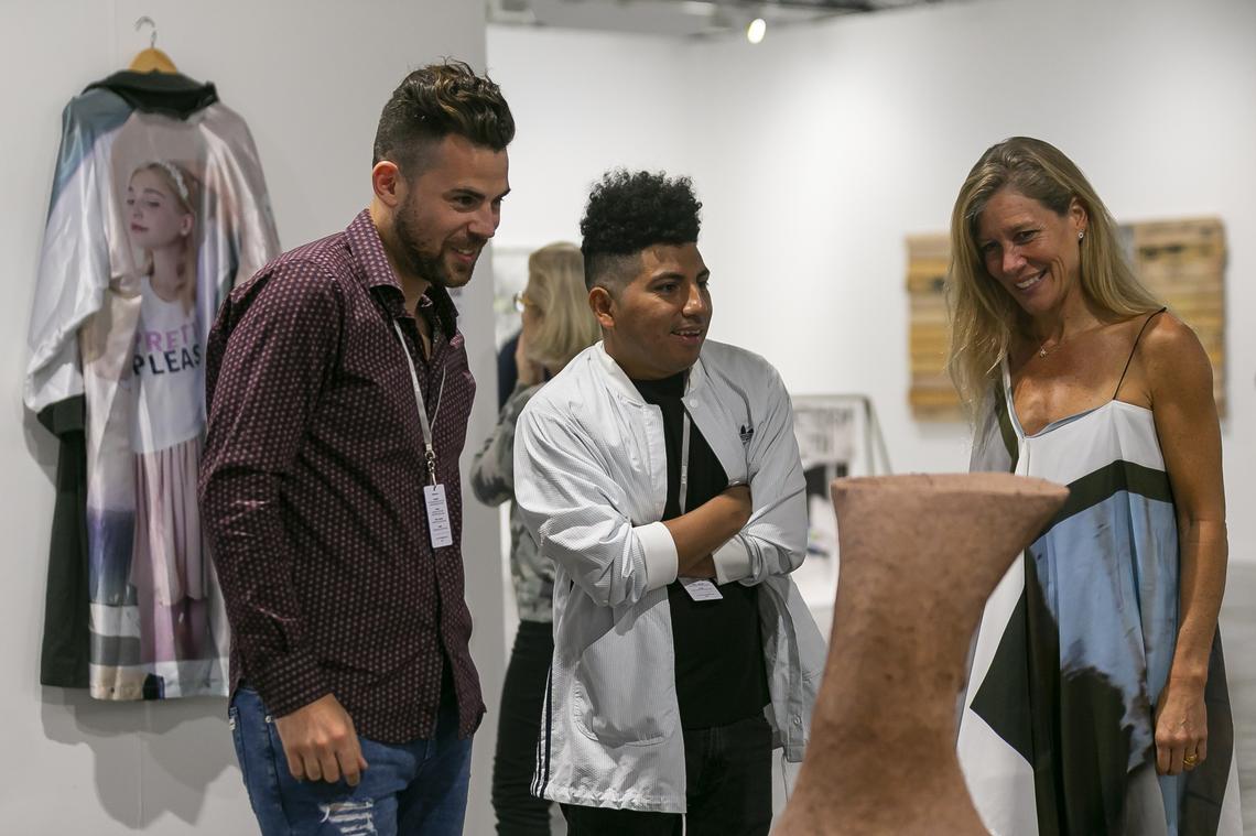 Kathryn Mikesell, at right, co-founder and director of the Fountainhead Residency for artists in Miami, talks with current program resident Gabriel Chaile, center, about his sculpture on exhibit at the Barro gallery booth during the Art Basel fair VIP opening at the Miami Beach Convention Center. Chaile, from Argentina, made the piece in Miami during his residency. At left is gallerist Federico Curutchet.