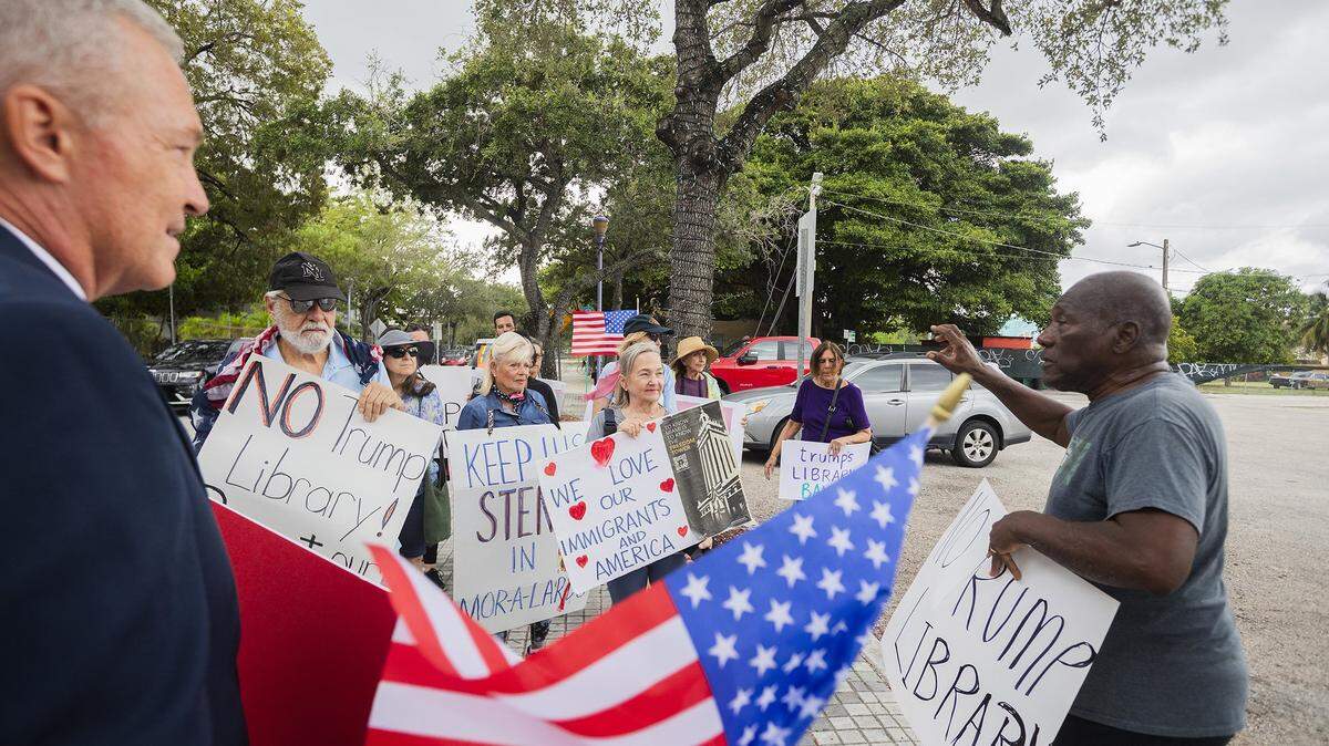 Phil Ehr, left, listens as activist and historian Marvin Dunn speaks to protesters outside the Kaseya Center during President Trump's appearance in Miami on Wednesday, Nov. 5, 2025. Demonstrators carried signs and chanted against his policies and a proposed land transfer for Trump's presidential library, raising concerns about public accountability and local institutions.