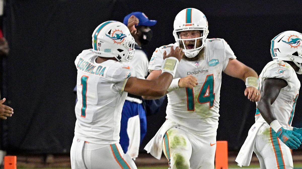Miami Dolphins quarterback Ryan Fitzpatrick (14) celebrates after throwing a touchdown pass against the Jacksonville Jaguars with teammate quarterback Tua Tagovailoa, left, during the first half of an NFL football game, Thursday, Sept. 24, 2020, in Jacksonville, Fla. (AP Photo/Phelan M. Ebenhack)