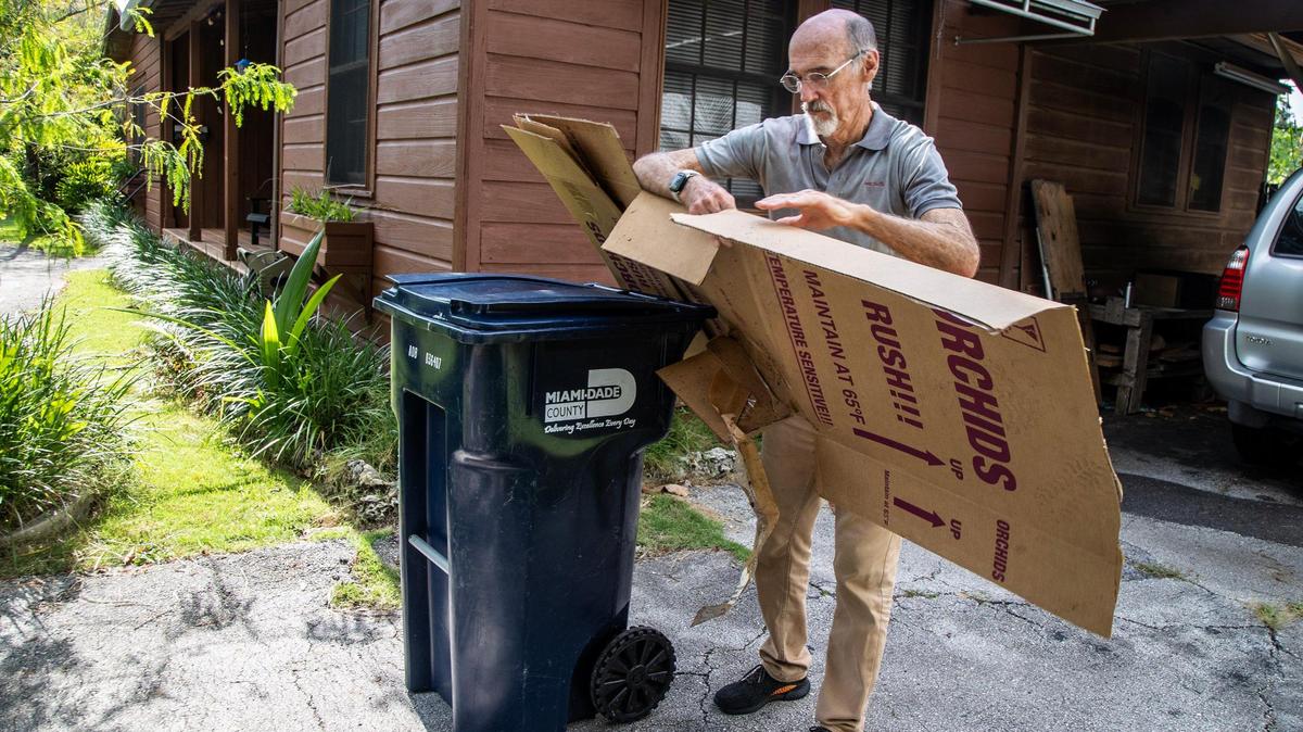 Noel Cleland, presidente de la sección local de Sierra Club, se prepara para depositar una caja de cartón en el contenedor de reciclaje de su casa en South Miami, el 4 de agosto de 2023..