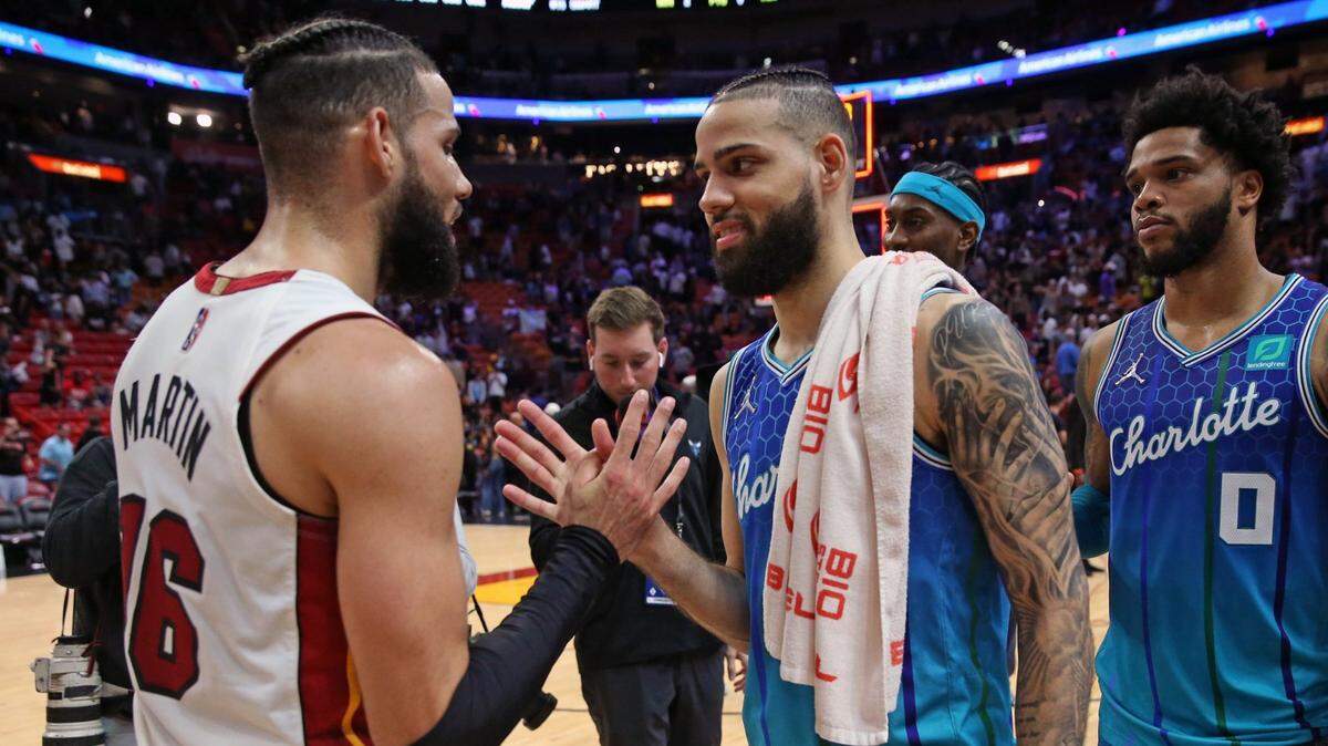 El jugador del Heat, Caleb Martin (izq.), y su hermano gemelo Cody Martin, de los Hornets de Charlotte, se saludan en la cancha después de un partido en el FTX Arena en Miami, Florida, el 5 de abril de 2022.