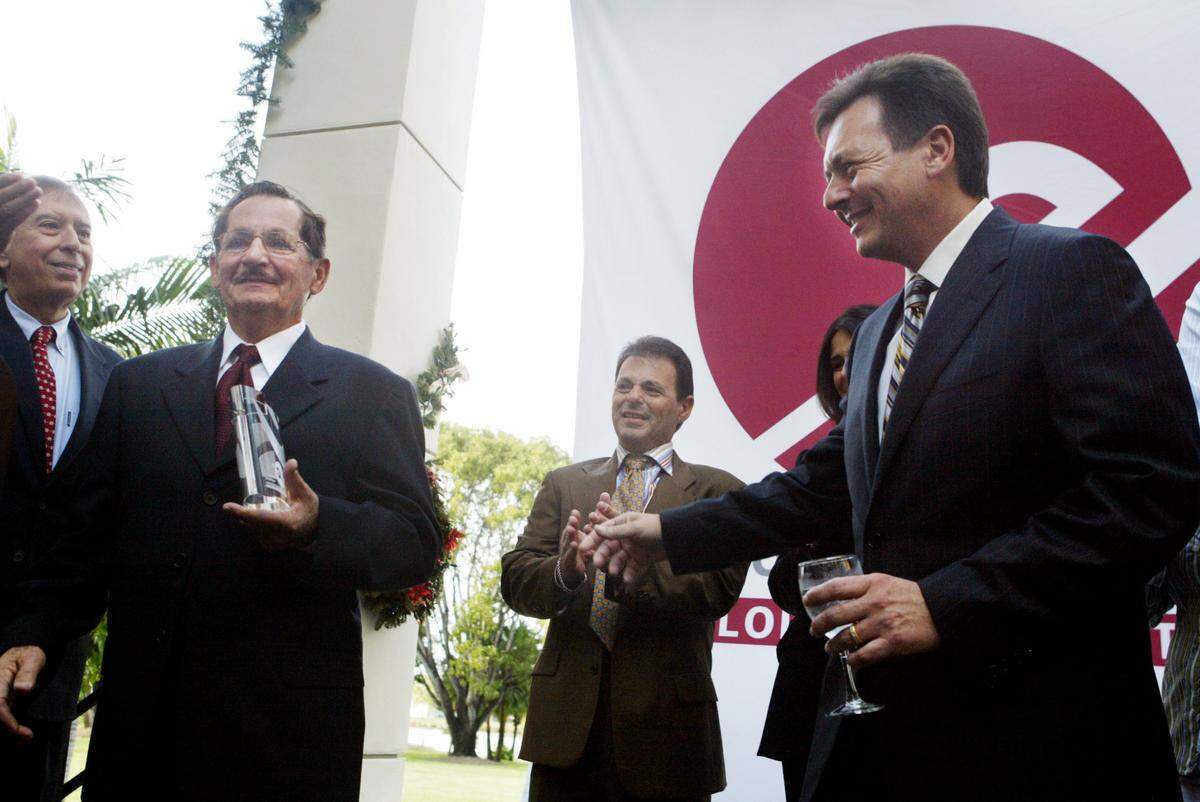 Sergio Pino, right, and his brother, Carlos Pino, second from right, watch as their father, Eugenio Pino, second from left, receives a plaque from Florida International University President Mitch Maidique, left, at FIU’s University House on Wednesday, Dec. 22, 2004. Sergio Pino of Century Builders Group gave $2 million to the FIU Global Entrepreneurship Center, now the Eugenio Pino and Family Global Entrepreneurship Center. Sergio surprised his father by honoring him with the donation.