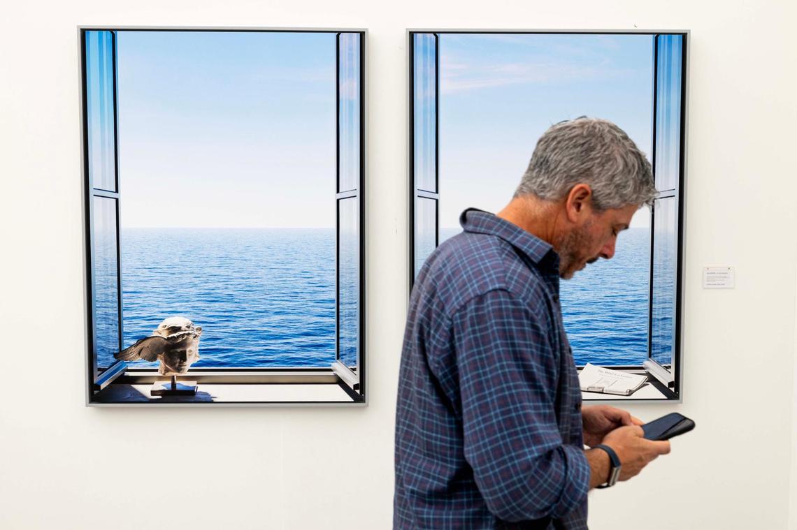 A man uses his cell phone as he walks past ‘Hypnos and Ocean (diptych) by Giuseppe Lo Schiavo at Untitled Art Fair on Tuesday, Dec. 3, 2024, in Miami Beach, Fla