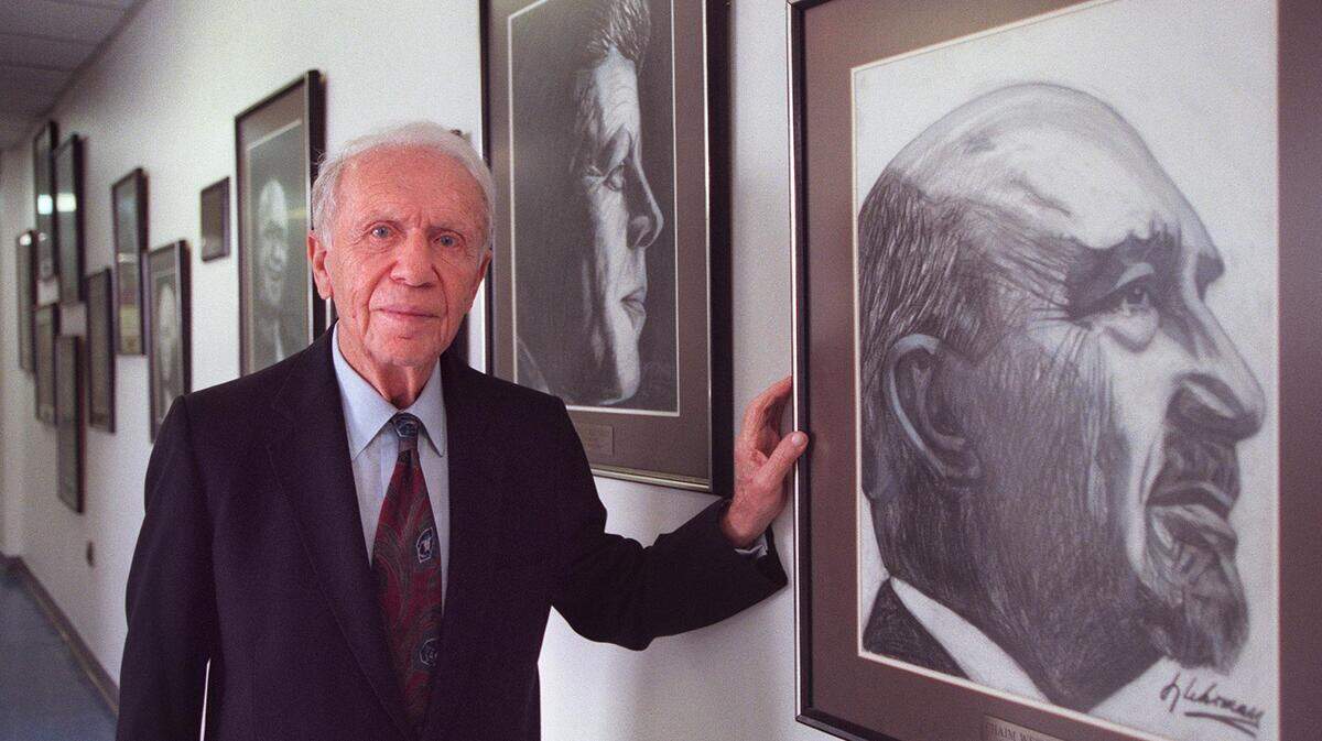 In this 1997 Miami Herald file photo, Rabbi Irving Lehrman stands by an exhibit of his charcoal portraits on display at Lehrman Day School in Miami Beach. He only draws people he likes and respects, he said. At right is a portrait of Chaim Weizmann, with a portrait of John F. Kennedy next to Rabbi Lehrman.