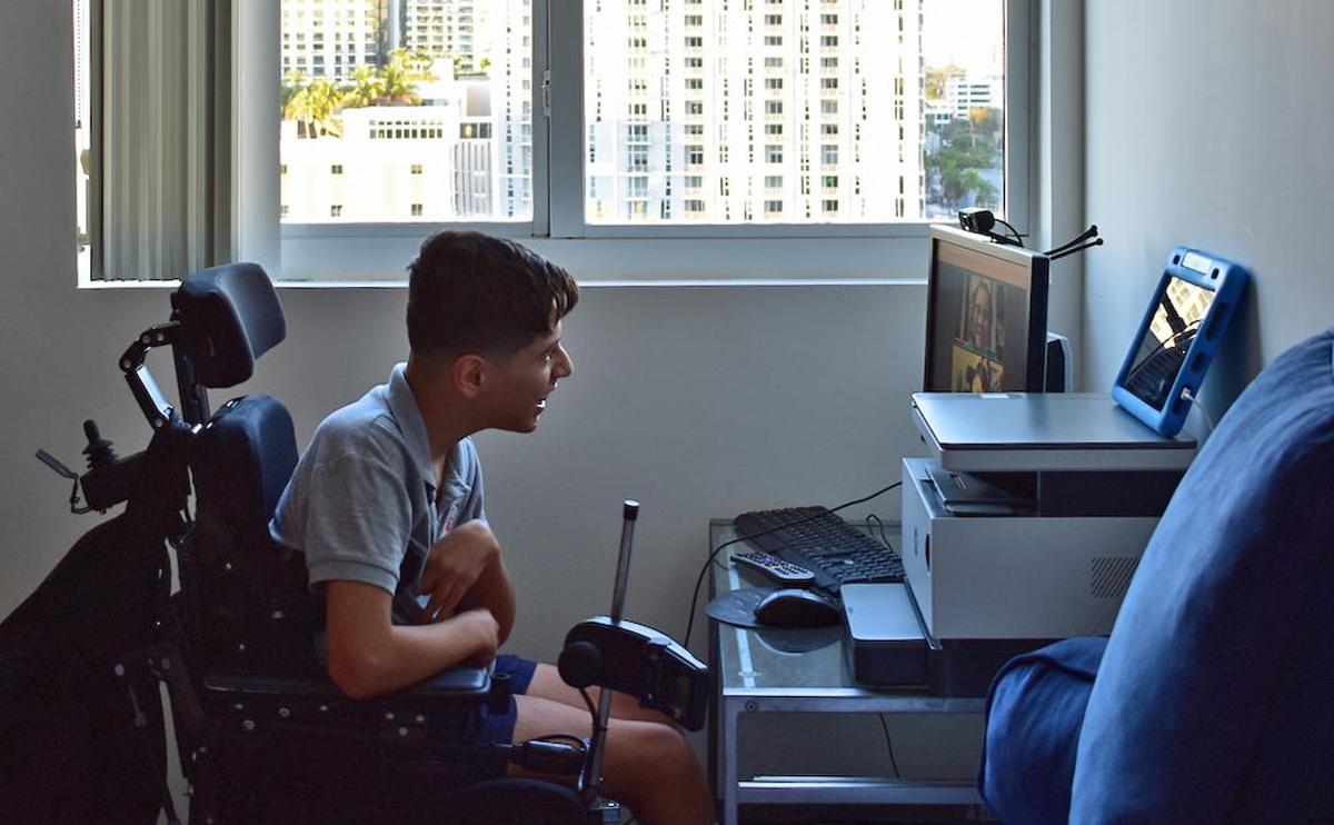 Juan Luna Bustamante, who has cerebral palsy, is at his desk for his online English lessons.