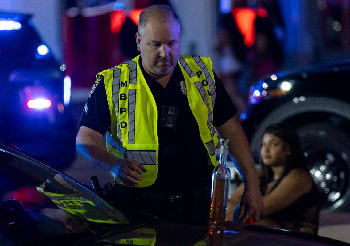 A Miami Beach police officer confiscates a liquor bottle at a DUI checkpoint at Meridian and 5th Street during spring break on Friday, March 15, 2024, in Miami Beach, Fla.&nbsp;
