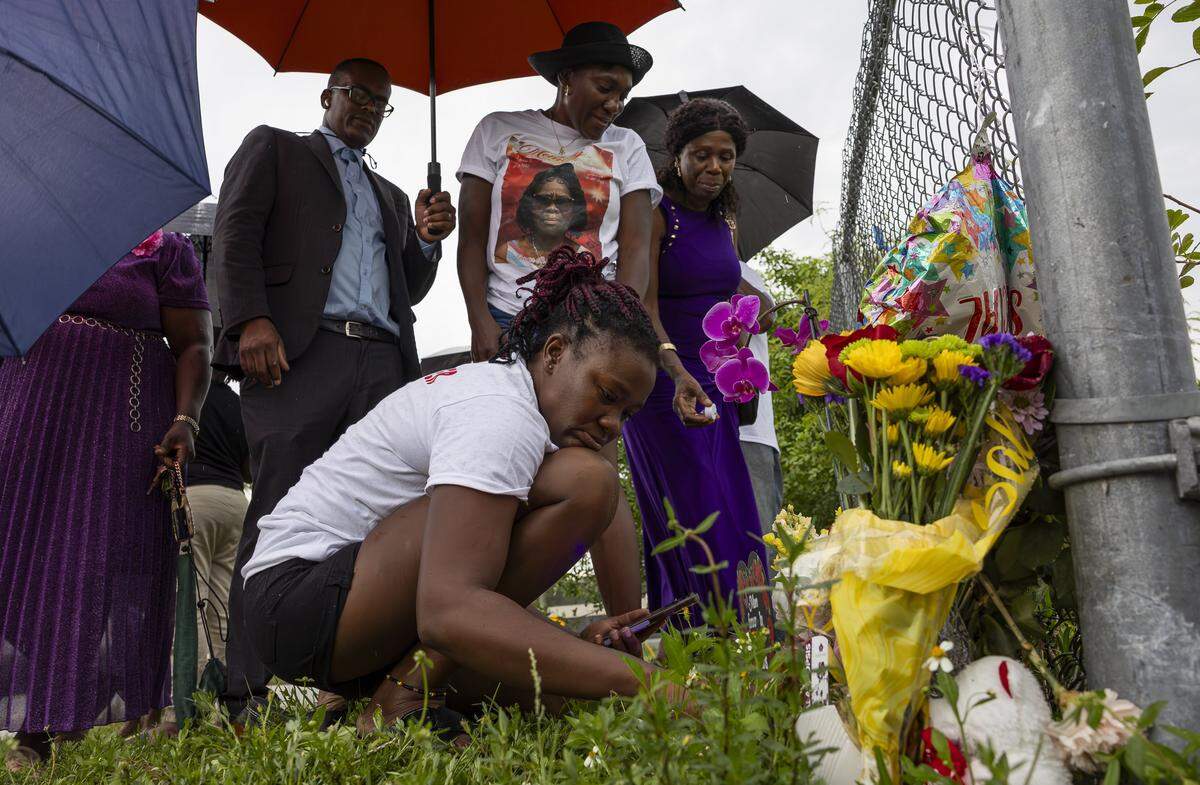 Lateisha Wilkinson, bottom center, and Shelley Ann Williams, top center, visit a makeshift memorial for their mother, Doreen Richards Broadbelt, 71, who police said was walking to her job at Walmart when a dog attacked and fatally mauled her near her home on Labor Day. A vigil was held nearby at Broadbelt’s home on Tuesday, Sept. 9, 2025, in Miami Gardens, Fla.