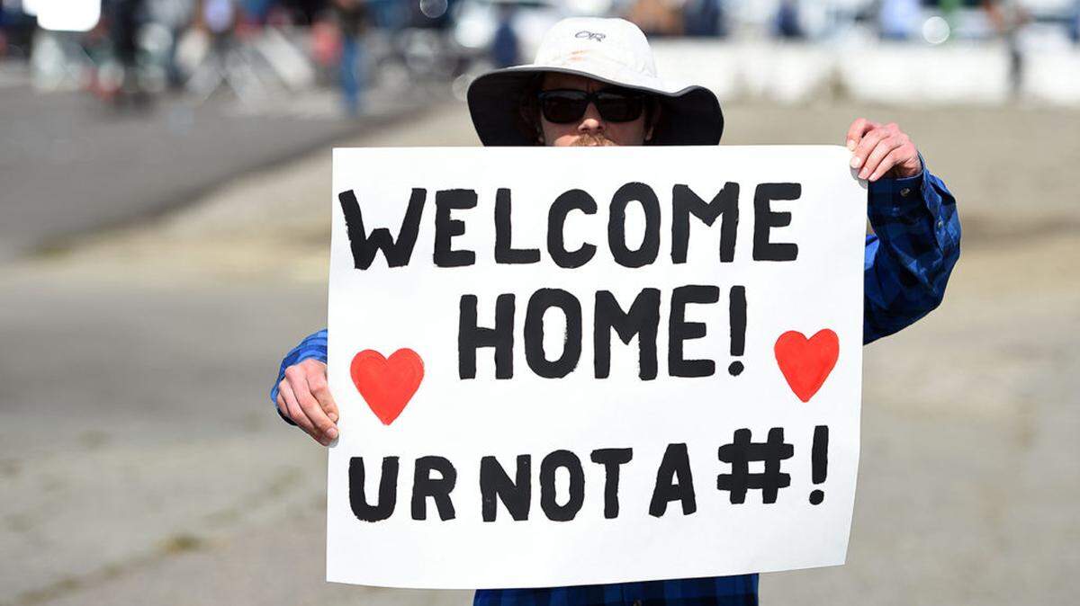 Eric Drake, in Oakland, California, holds his message for cruise passengers from the Grand Princess after they were stuck at sea when at least 21 people tested positive for the coronavirus in March.