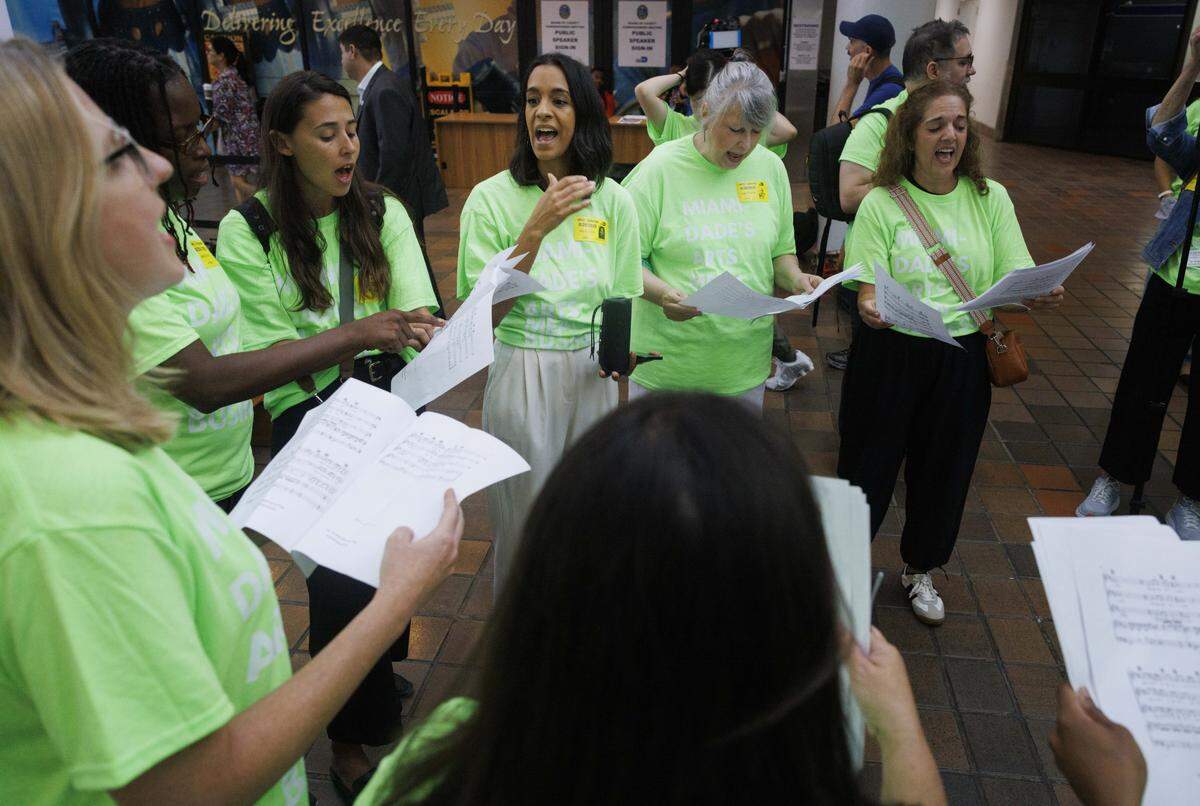 Jaime Sutta, center, executive director of Vocal Youth Miami, leads a singing group during an Arts Action Miami protest on Wednesday, Aug. 20, 2025, at the Stephen P. Clark Government Center in downtown Miami. Artists, arts leaders, and community members gathered to protect cultural funding and keep the Department of Cultural Affairs independent.