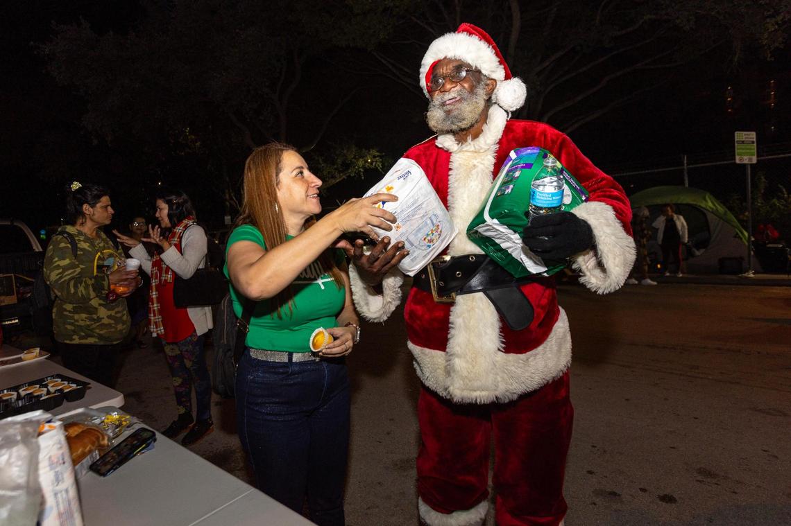 Unhoused man Jeffrey Redding, 53, and Hermanos de la Calle volunteer Carolina Montoya, 46, during a Christmas food distribution event on NW 17th Street in Miami, Florida, on Friday, December 22, 2023. The faith based organization Hermanos de la Calle and members of various local congregations helped feed the unsheltered and assisted people with finding shelter.