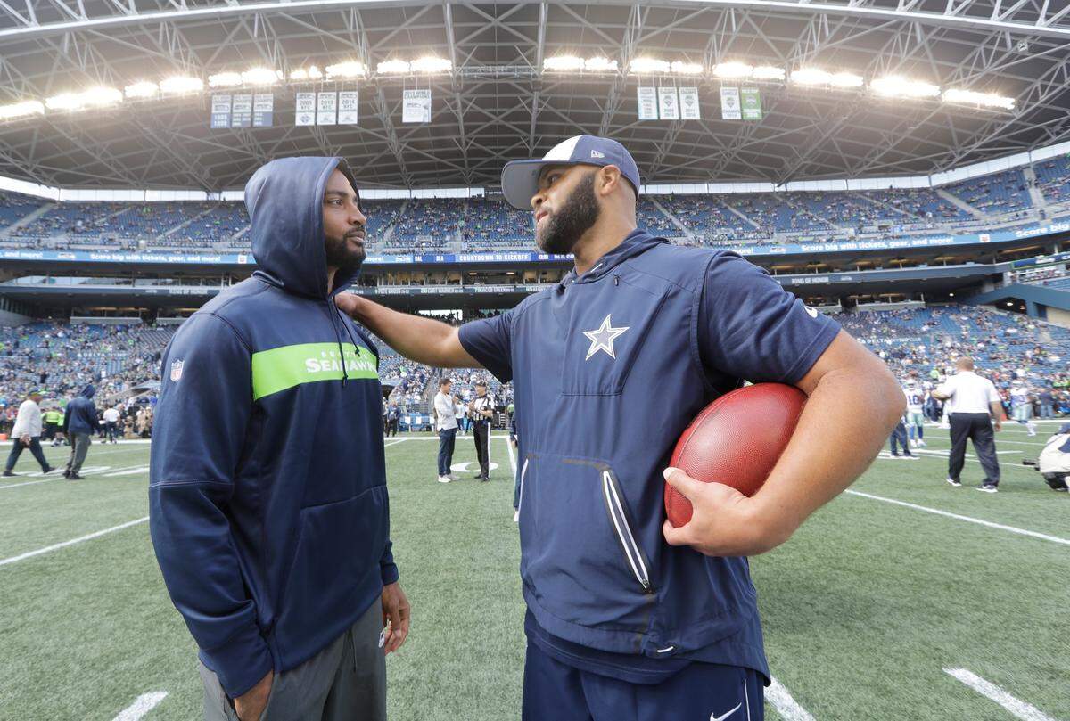 Dallas Cowboys defensive backs coach and passing game coordinator Kris Richard, right, greets injured Seattle Seahawks wide receiver Doug Baldwin, left, before an NFL football game, Sunday, Sept. 23, 2018, in Seattle. Richard is the former defensive coordinator for the Seahawks. (AP Photo/Elaine Thompson)