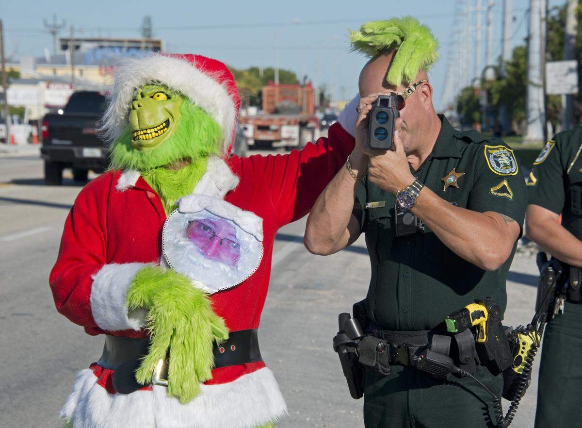 Monroe County Sheriff’s Office Col. Lou Caputo, left, has some fun with Deputy Willie Guerra as he aims a radar speed gun in a school zone on the Florida Keys Overseas Highway Tuesday, Dec. 12, 2017, in Marathon, Fla. During the holiday season, Caputo dresses as the Grinch to provide motorists who slightly speed in the zone the option of a traffic citation or an onion. FOR EDITORIAL USE ONLY (Andy Newman/Florida Keys News Bureau/HO)