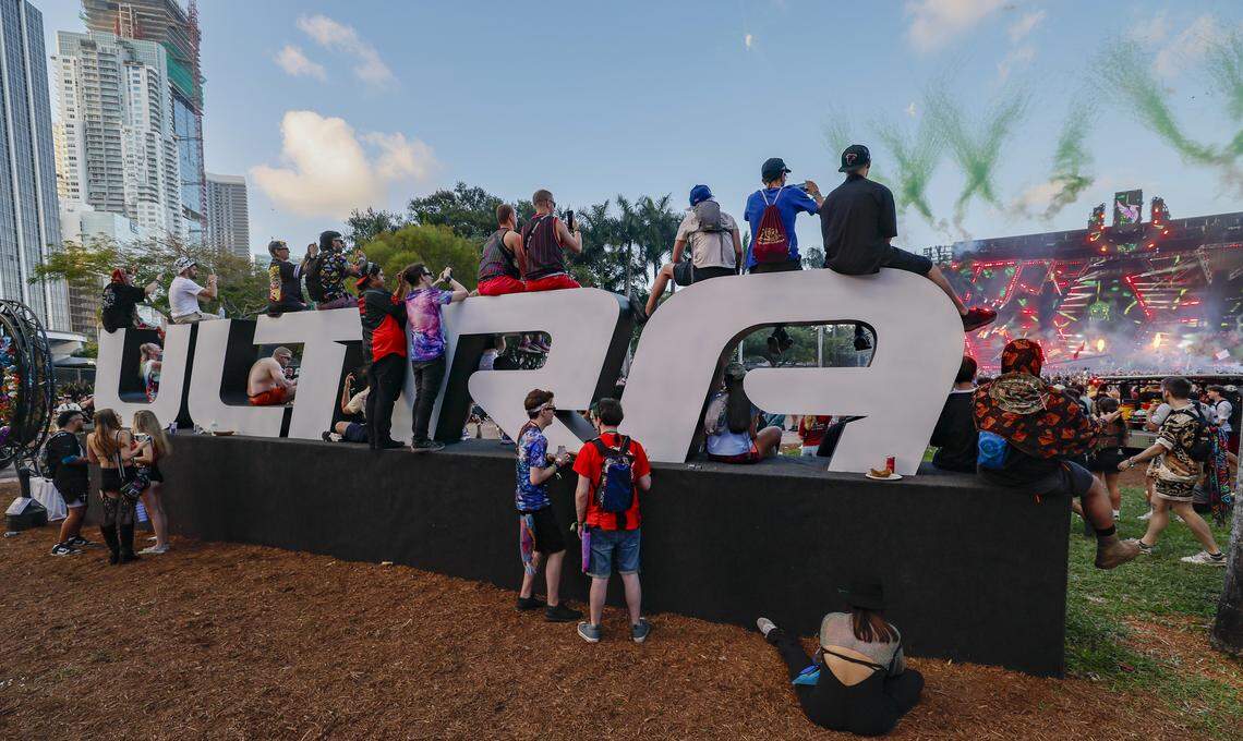 EDM fans sit on the Ultra name dispaly near the Main Stage at Ultra Music Festival in Miami, Florida, on Friday, March 27, 2026.